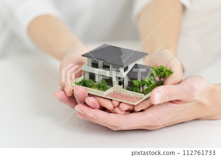 Hands of a man and woman holding a model of a house 112761733