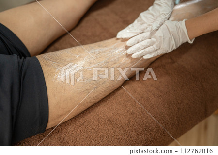 Esthetician and man massaging legs at men's beauty/hair removal salon Esthetician and man massaging legs at men's beauty/hair removal salon 112762016