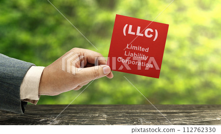 Business hand holding a note with LLC text, the acronym of Limited Liability Company Business hand holding a note with LLC text, the acronym of Limited Liability Company 112762330