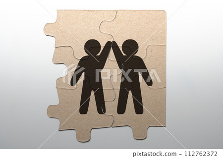 Closeup view of a human giving a high five in the piece of the puzzle for unity and teamwork Closeup view of a human giving a high five in the piece of the puzzle for unity and teamwork 112762372
