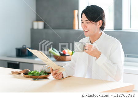 Young Asian man drinking coffee while reading a newspaper 112763788