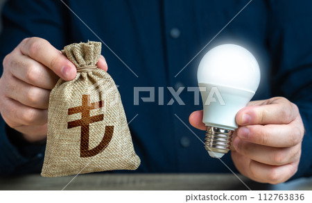 Turkish lira money bag and burning idea light bulb in the hands of a man. Reduce carbon footprint. Investment in an idea. Offering financial incentives to enhancing energy efficiency. Turkish lira money bag and burning idea light bulb in the hands of a man. Reduce carbon footprint. Investment in an idea. Offering financial incentives to enhancing energy efficiency. 112763836