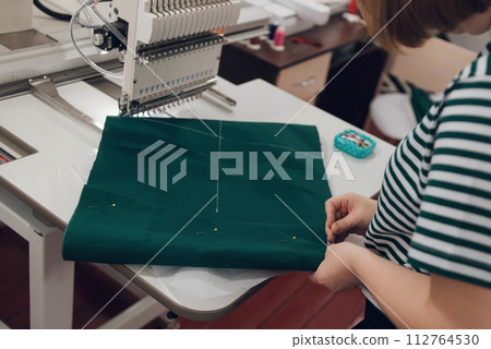 girl works on an embroidery machine at home, sets up and prepares the machine for work girl works on an embroidery machine at home, sets up and prepares the machine for work 112764530