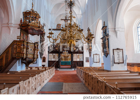 Bright, airy church in Copenhagen or Malmo with white walls, arched ceilings, and a central aisle to a blue altar. Boasts a grand chandelier, carved wooden pulpit, and orderly pew rows. 112765915