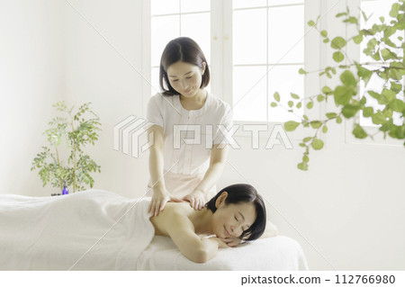 一名中年婦女在美容院接受年輕美容師的治療。 112766980