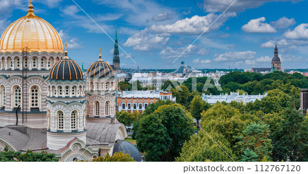 The Nativity of Christ Cathedral in Riga, Latvia. Byzantine-styled Orthodox cathedral, the largest in the Baltic region, with golden colored dome, polished gilded cupolas gleaming through the trees The Nativity of Christ Cathedral in Riga, Latvia. Byzantine-styled Orthodox cathedral, the largest in the Baltic region, with golden colored dome, polished gilded cupolas gleaming through the trees 112767120