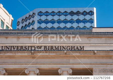 A classical University of Birmingham facade with UNIVERSITY OF BIRMINGHAM inscribed, contrasts a modern building with a honeycomblike design and blue windows in Birmingham, UK. A classical University of Birmingham facade with UNIVERSITY OF BIRMINGHAM inscribed, contrasts a modern building with a honeycomblike design and blue windows in Birmingham, UK. 112767208