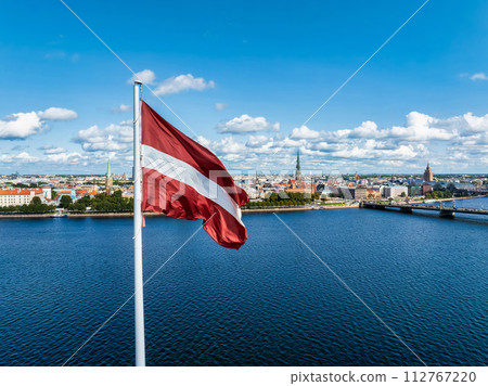 Beautiful Latvian flag flutters on wind with Riga old town in the background in Latvia. Patriotic video. Panoramic view. Beautiful Latvian flag flutters on wind with Riga old town in the background in Latvia. Patriotic video. Panoramic view. 112767220