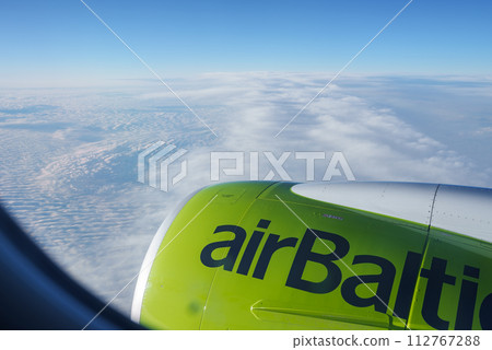 Bright lime green airBaltic engine cowling captures attention in this aerial view, reflecting the blue sky and overlooking a sea of clouds. Ideal for travelers seeking highaltitude serenity. Bright lime green airBaltic engine cowling captures attention in this aerial view, reflecting the blue sky and overlooking a sea of clouds. Ideal for travelers seeking highaltitude serenity. 112767288