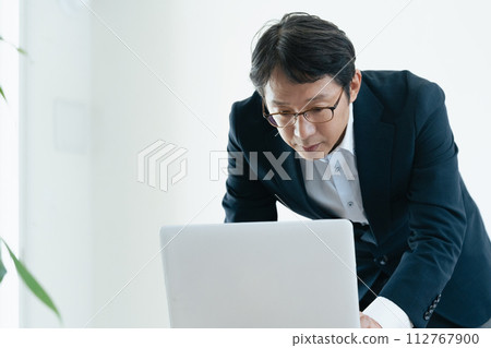 Businessman worried while looking at a computer Businessman worried while looking at a computer 112767900
