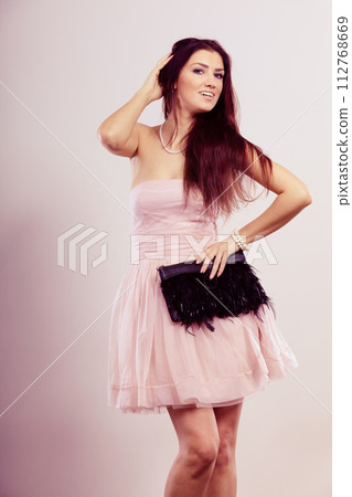 Brunette woman in bright dress with clutch bag 112768669