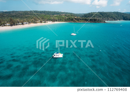 Boat floating on blue water at tropical island 112769408