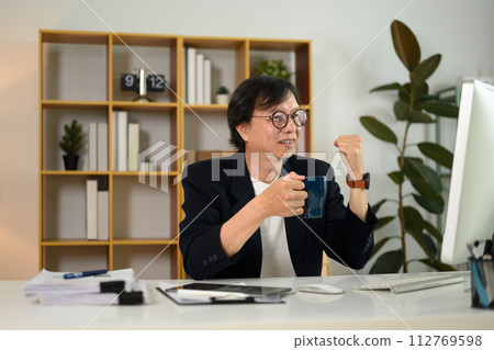 Happy middle age businessman raising hands celebrating success in the office 112769598