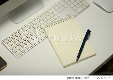 Top view of notepad, computer keyboard and mouse on white office desk 112769696