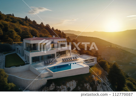an aerial view of a house with a swimming pool on top of a hill at sunset 112770087