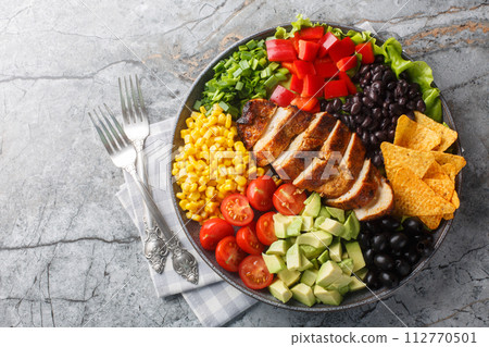 Southwest salad of chicken, corn, peppers, olives, avocado, tomatoes and onions close-up on a board. Horizontal top view Southwest salad of chicken, corn, peppers, olives, avocado, tomatoes and onions close-up on a board. Horizontal top view 112770501
