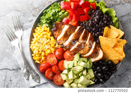 Tex-Mex Santa Fe chicken salad with lettuce, tomatoes, corn, black beans, pepper, avocado, olive closeup on the plate. Horizontal top view Tex-Mex Santa Fe chicken salad with lettuce, tomatoes, corn, black beans, pepper, avocado, olive closeup on the plate. Horizontal top view 112770502