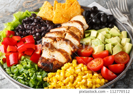 Southwest salad of chicken, corn, peppers, olives, avocado, tomatoes and onions close-up on the plate. Horizontal 112770512