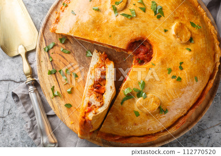 Delicious Empanada Gallega round Spanish pie filled with meat and vegetables close-up on a board. Horizontal top view 112770520