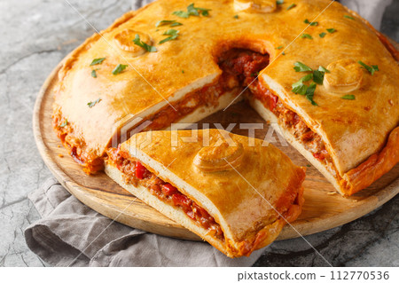 Homemade Empanada Gallega large Spanish pie filled with meat or fish and vegetables close-up on a board. Horizontal Homemade Empanada Gallega large Spanish pie filled with meat or fish and vegetables close-up on a board. Horizontal 112770536