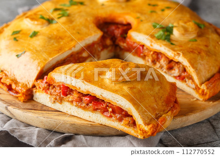 Delicious Empanada Gallega round Spanish pie filled with meat and vegetables close-up on a board. Horizontal 112770552
