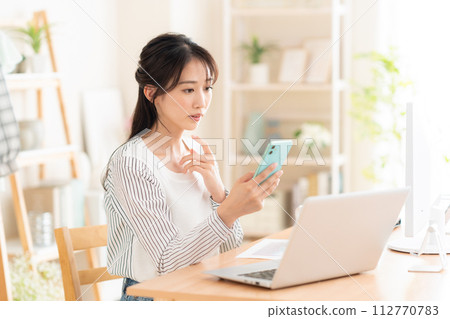 一名年輕女子在遠距辦公期間在客廳工作 112770783