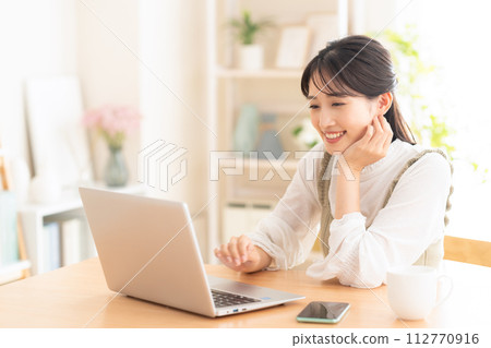 A young woman looking at a computer in the living room A young woman looking at a computer in the living room 112770916