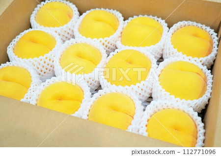 12 beautiful yellow peaches hung in white bubble wrap packed in cardboard 112771096