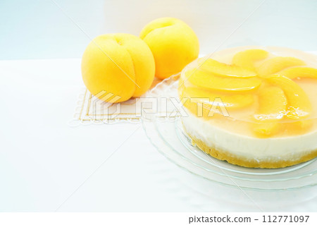 A cool two-layered rare cheesecake hall decorated with yellow peaches on a white background 112771097