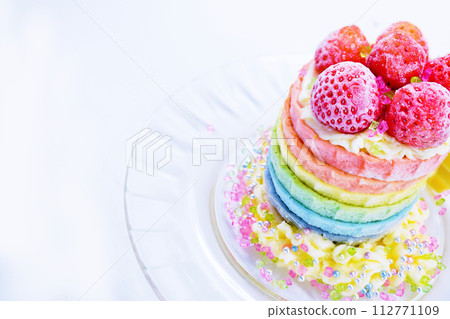 Cute sparkling rainbow cake with red strawberries on a simple white background, overhead view Cute sparkling rainbow cake with red strawberries on a simple white background, overhead view 112771109