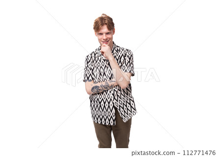 young focused caucasian man with red hair with a tattoo dressed in a summer black and white shirt on 112771476