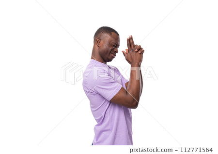 a young positive friendly American man with a short haircut is dressed in a lilac T-shirt standing 112771564