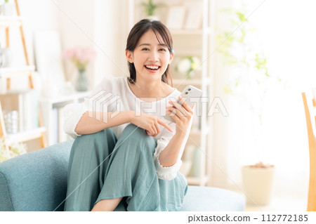 年輕女子在客廳看智慧型手機 112772185