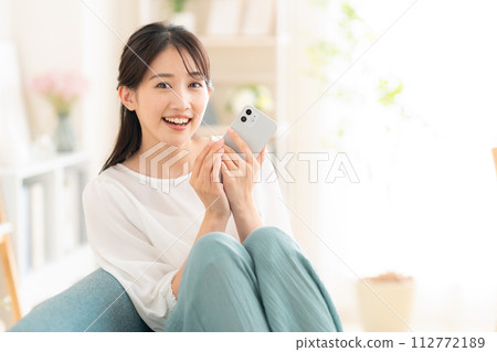 年輕女子在客廳看智慧型手機 112772189