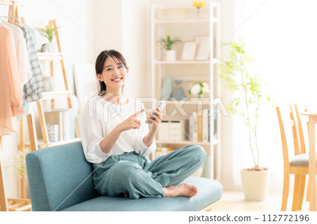 Young woman looking at her smartphone in the living room 112772196