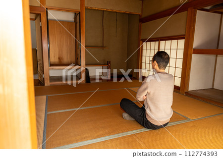 A middle-aged man sits in a Japanese-style room deep in thought after sorting through the belongings of his parents' house and carrying out all the belongings inside. A middle-aged man sits in a Japanese-style room deep in thought after sorting through the belongings of his parents' house and carrying out all the belongings inside. 112774393