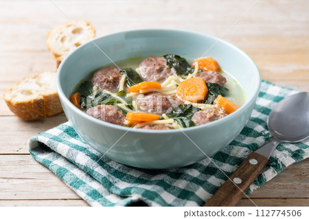Italian Wedding Soup with meatballs and spinach on wooden table Italian Wedding Soup with meatballs and spinach on wooden table 112774506