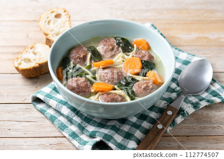 Italian Wedding Soup with meatballs and spinach on wooden table Italian Wedding Soup with meatballs and spinach on wooden table 112774507