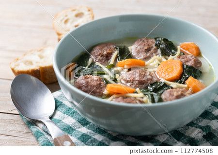Italian Wedding Soup with meatballs and spinach on wooden table Italian Wedding Soup with meatballs and spinach on wooden table 112774508