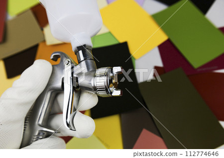 paint spray gun at work at the workplace in the workshop, selection of tools, paint samples 112774646