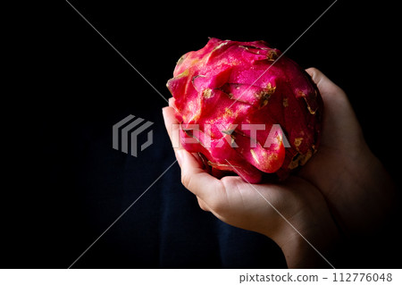 holding a dragon fruit in hand 112776048