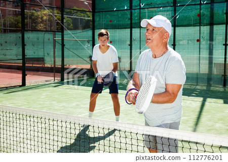 Padel players of different generations playing padel court Padel players of different generations playing padel court 112776201