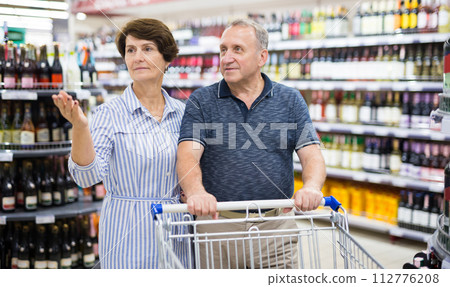 Mature couple husband and wife choose alcoholic drinks in supermarket 112776208
