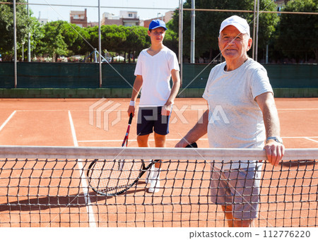 Senior man posing on tennis court Senior man posing on tennis court 112776220