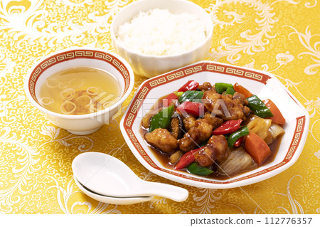 糖醋肉是一道經典的中國菜餚,盛在八角形的盤子上,上面覆蓋著黃色的中國圖案布。 糖醋肉是一道經典的中國菜餚,盛在八角形的盤子上,上面覆蓋著黃色的中國圖案布。 112776357