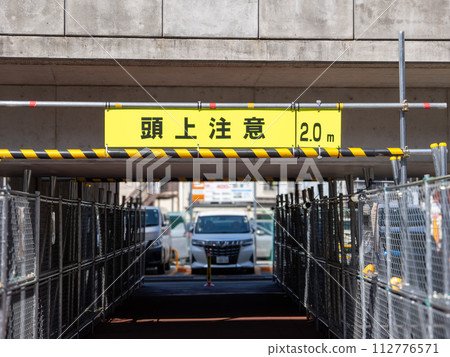 A sign indicating the height limit for pedestrian walkways under elevated tracks: ``Caution Overhead'' 112776571