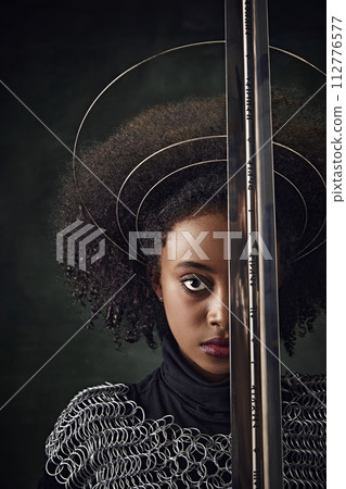 Half-face portrait of African woman with circular halos around her head and chainmail attire holding sword close face on dark vintage background Half-face portrait of African woman with circular halos around her head and chainmail attire holding sword close face on dark vintage background 112776577