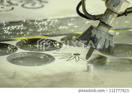 The multi axis abrasive waterjet cutting machine cutting the metal plate in the light blue scene. The multi axis abrasive waterjet cutting machine cutting the metal plate in the light blue scene. 112777823