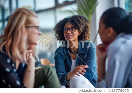 Three women in a casual setting deeply involved in a heartfelt discussion indoors 112778055
