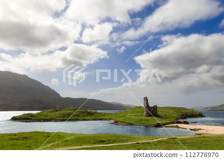 Ardvreck Castle ruin on lush islet under dynamic sky by Loch Assynt's tranquil waters Ardvreck Castle ruin on lush islet under dynamic sky by Loch Assynt's tranquil waters 112778970